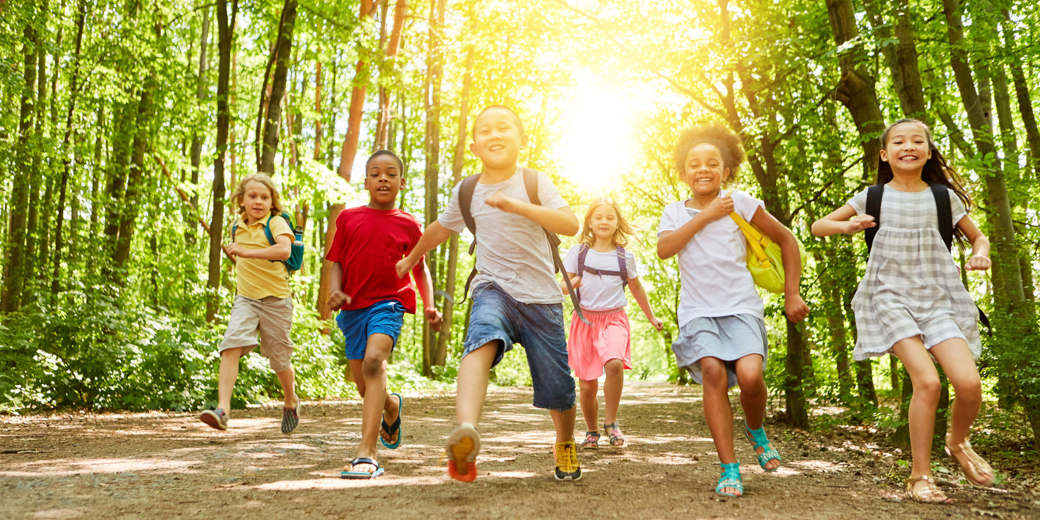 Happy kids run together to summer camp in nature